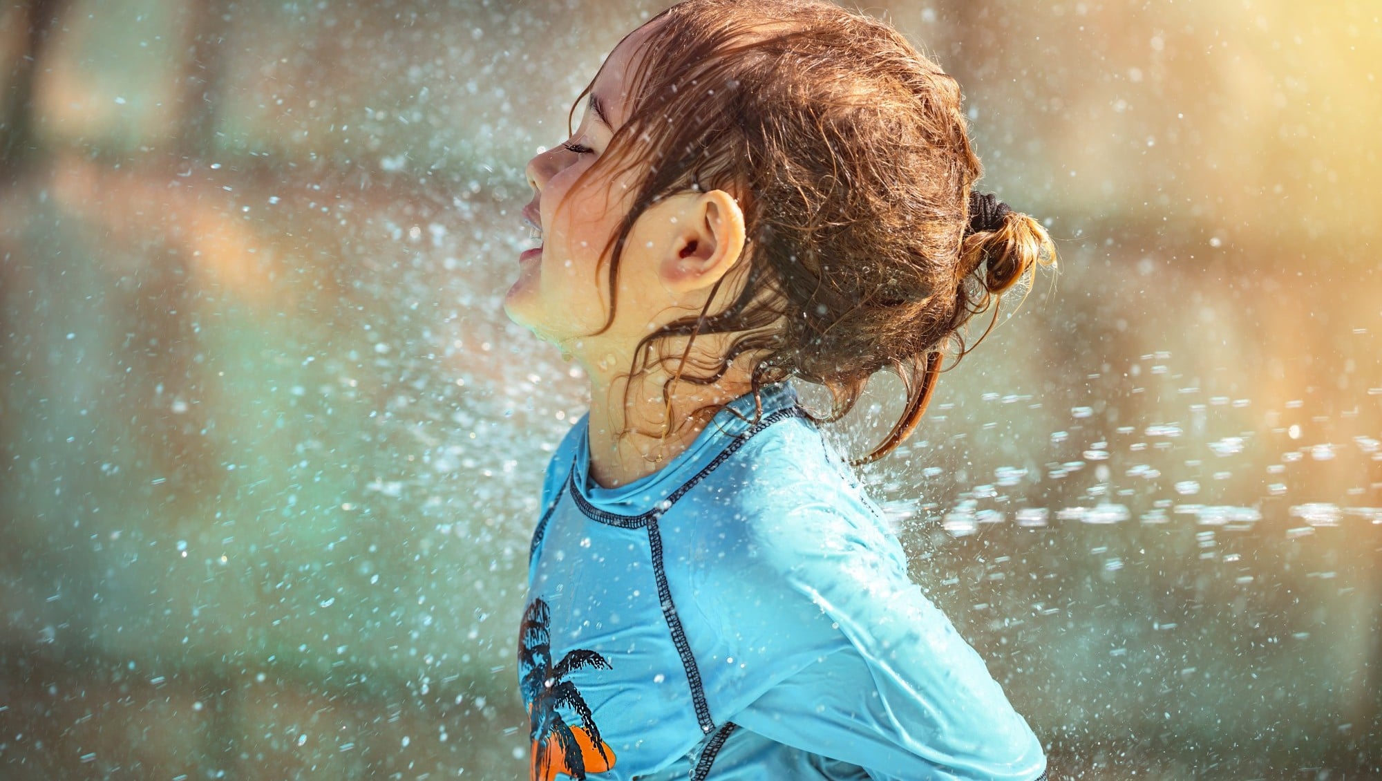 Happy kid enjoying a water shower in waterpark